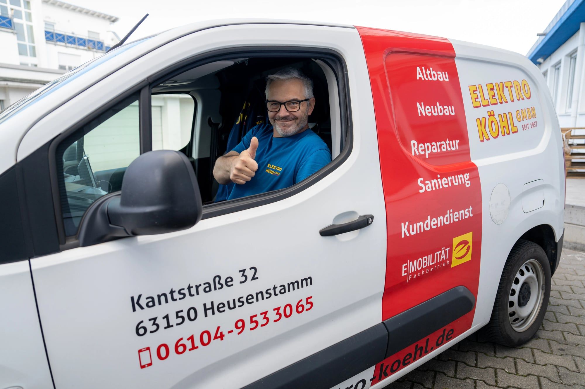 Monteur von Elektro Köhl zeigt aus dem Firmenfahrzeug den Daumen nach oben